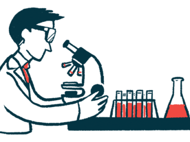 A scientist looks into a microscope located next to a rack of filled test tubes and a beaker.