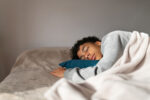 A boy with curly hair is seen sleeping on his side.
