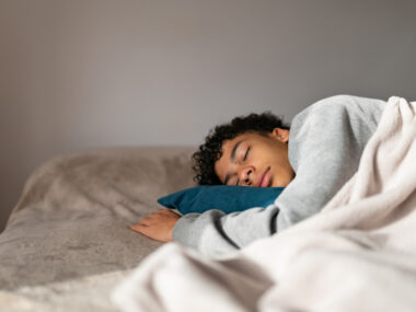 A boy with curly hair is seen sleeping on his side.