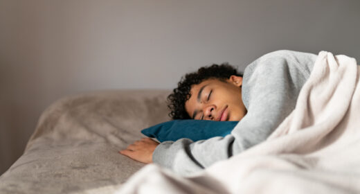 A boy with curly hair is seen sleeping on his side.