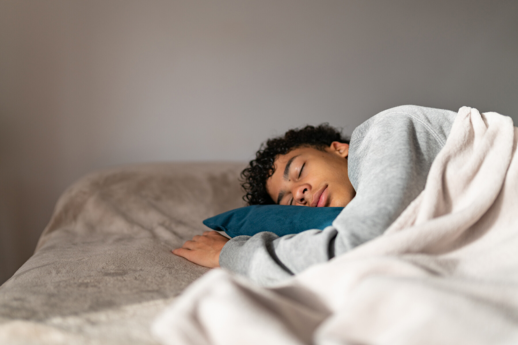 A boy with curly hair is seen sleeping on his side.
