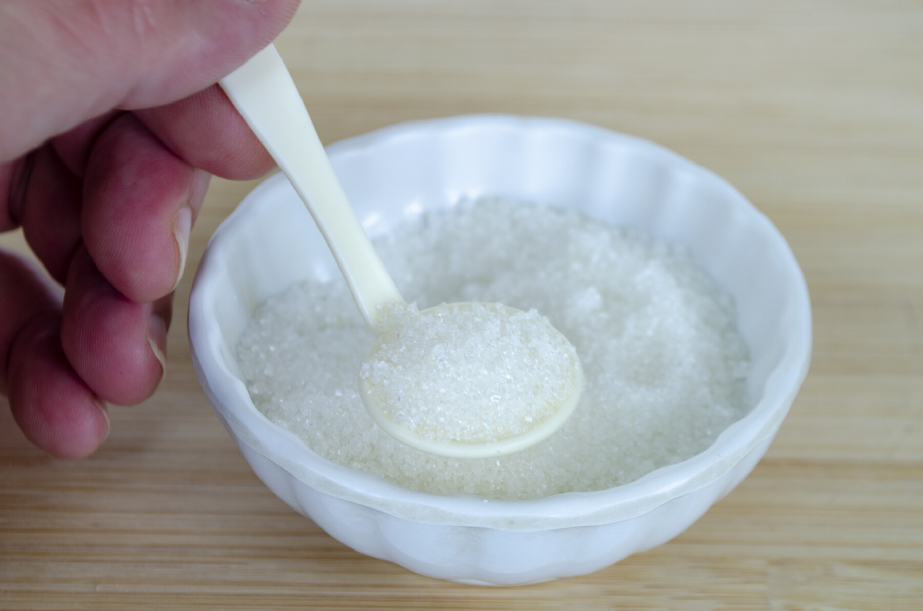 A photograph shows a hand holding a spoonful of salt in a salt cellar.