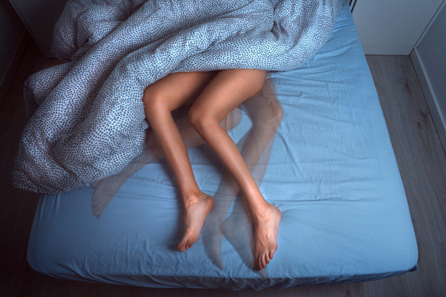 A woman's legs are shown with the rest of her body under blankets.