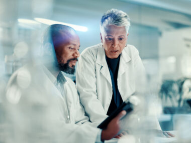 Two researchers in a lab confer about data.