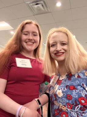 Two women, one middle-aged and one college-aged, smile for a selfie together.