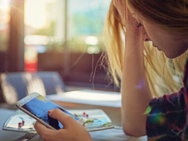 A girl looks at a broken mobile phone.